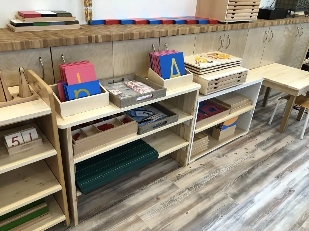 Low open shelves lined with Montessori materials, each with its own place